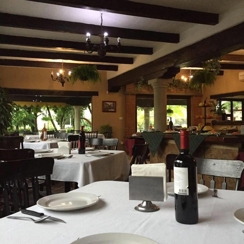 Salón interior de Larrabezúa con mesas, vigas de madera y vegetación